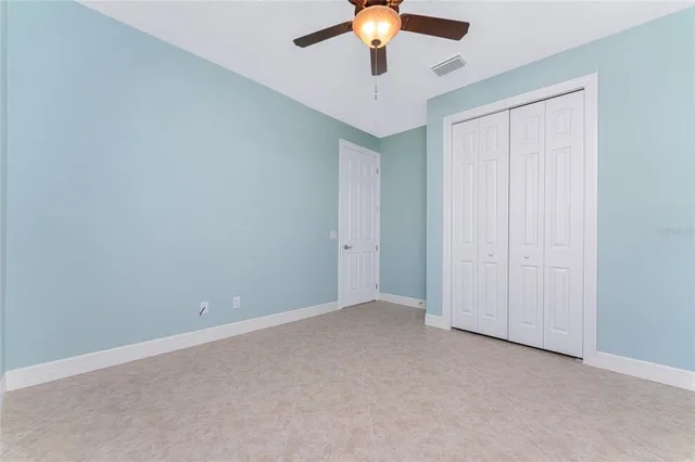 an empty room with a ceiling fan and carpet