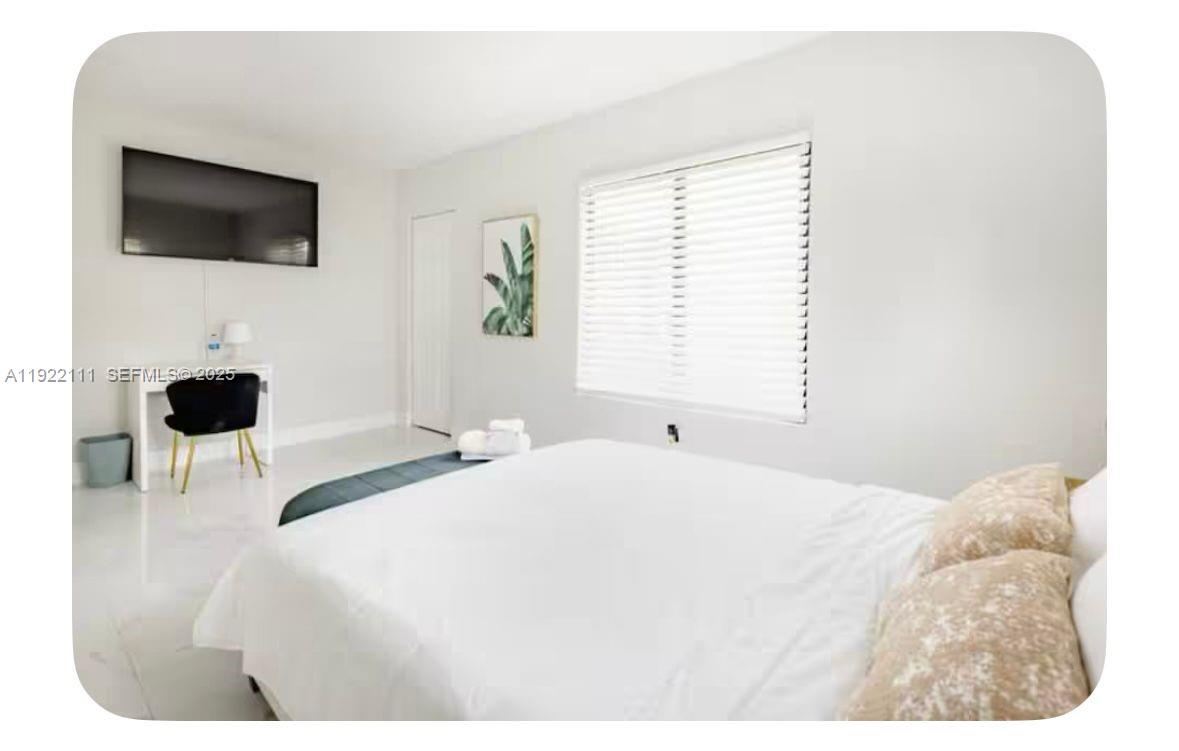 1301 Northwest 99th Street, Unit A Miami, FL 33147 - Photo 7 of 10 a bedroom with a bed a flat screen tv and a window