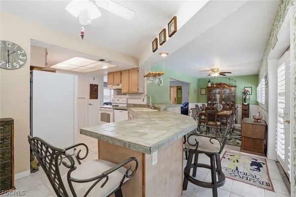 a kitchen with stainless steel appliances kitchen island granite countertop a dining table chairs and a refrigerator