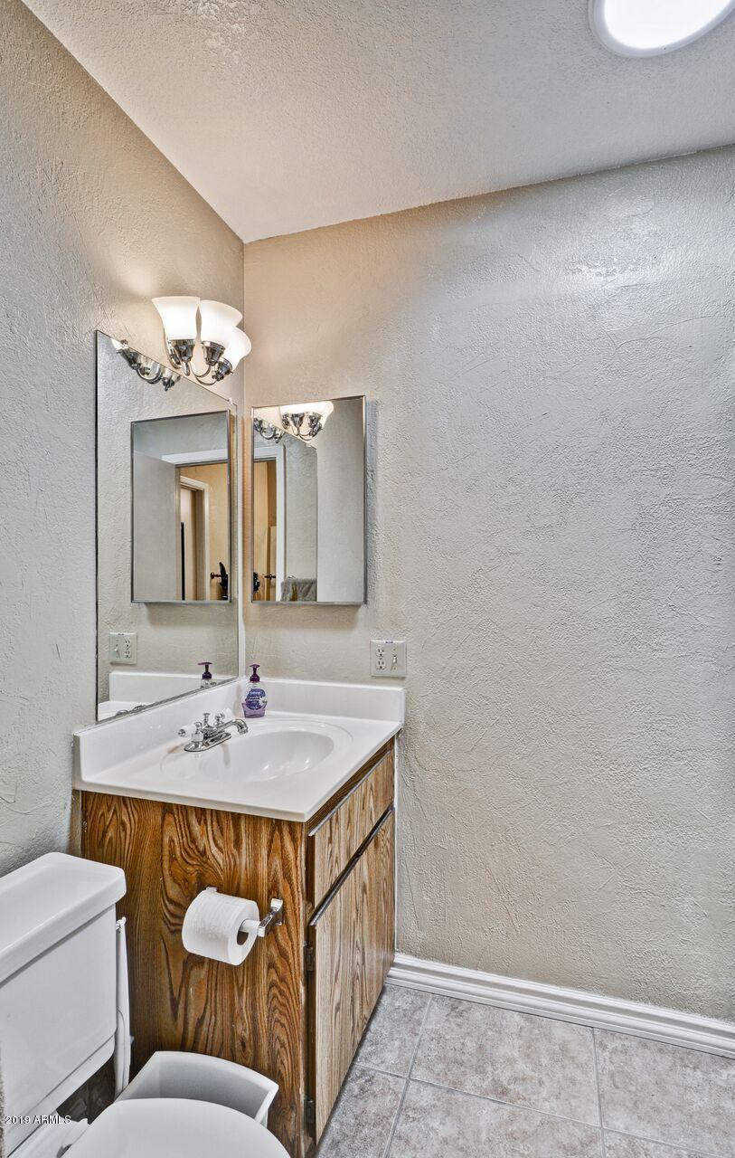 14300 West Bell Road, Unit 162 Surprise, AZ 85374 - Photo 11 of 23 a bathroom with a sink a toilet a mirror and vanity