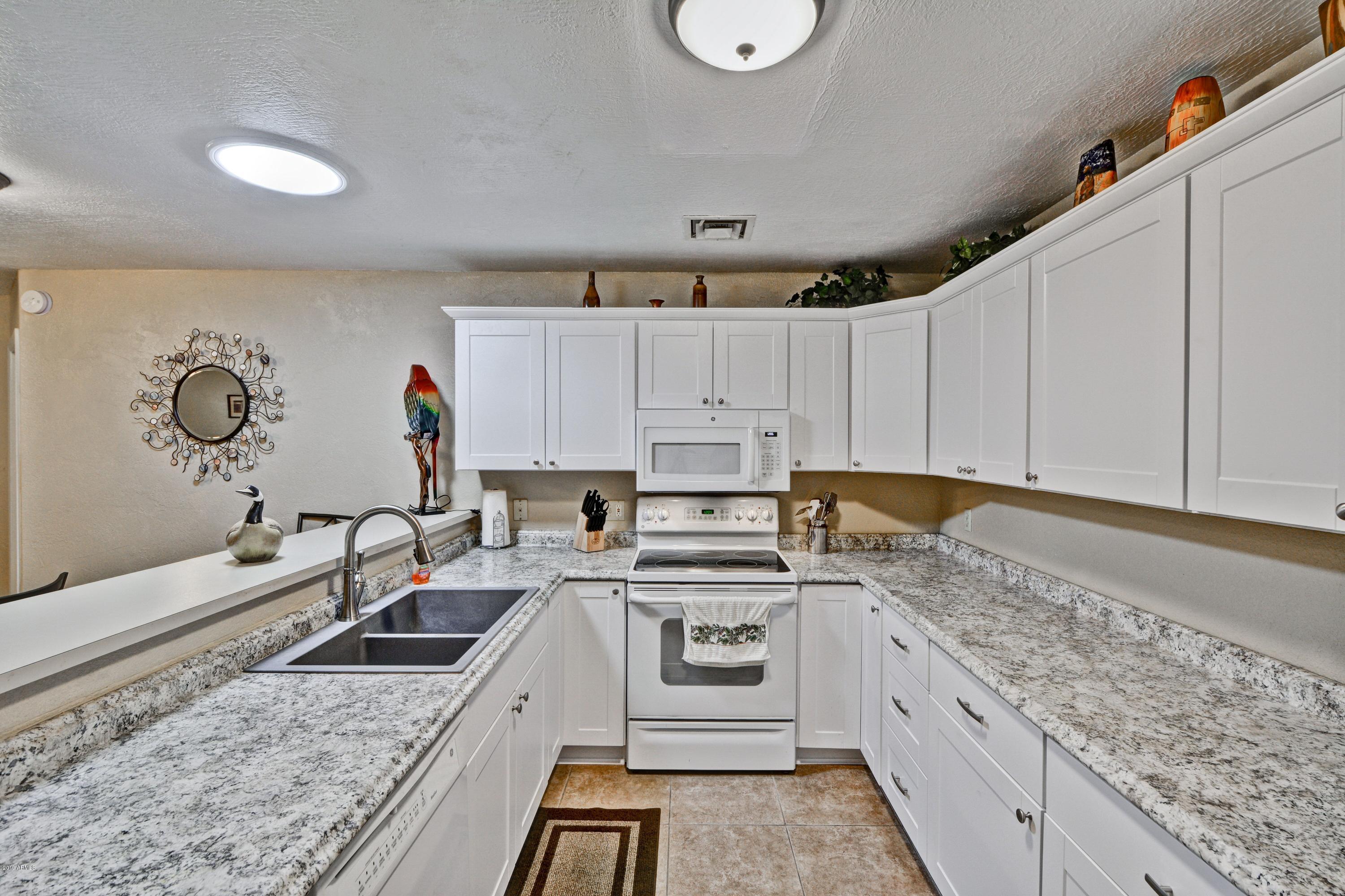 14300 West Bell Road, Unit 162 Surprise, AZ 85374 - Photo 3 of 23 a kitchen with granite countertop a sink a stove and cabinets
