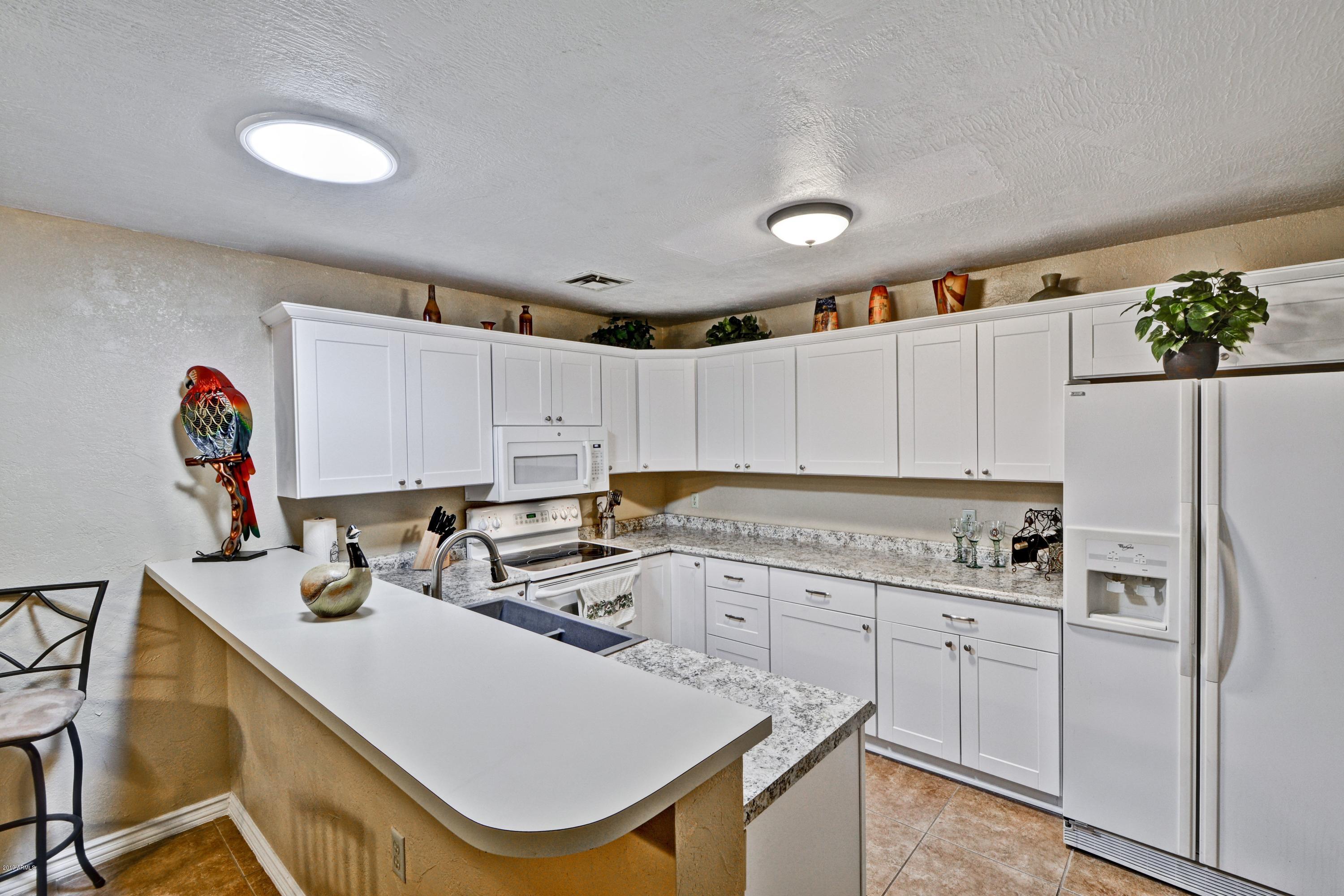 14300 West Bell Road, Unit 162 Surprise, AZ 85374 - Photo 6 of 23 a kitchen with a refrigerator a sink and cabinets