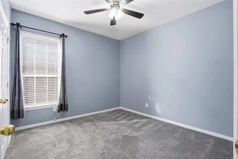 an empty room with a window and a ceiling fan