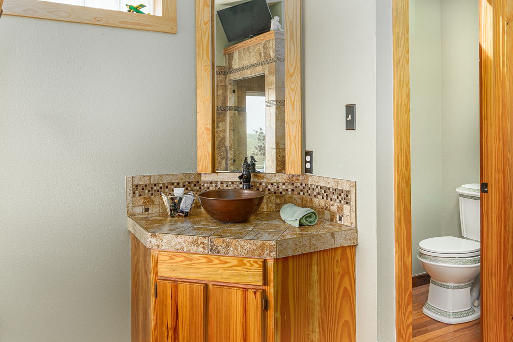 290 Japonica Road Hunt, TX 78024 - Photo 33 of 78 a bathroom with a granite countertop sink and a toilet