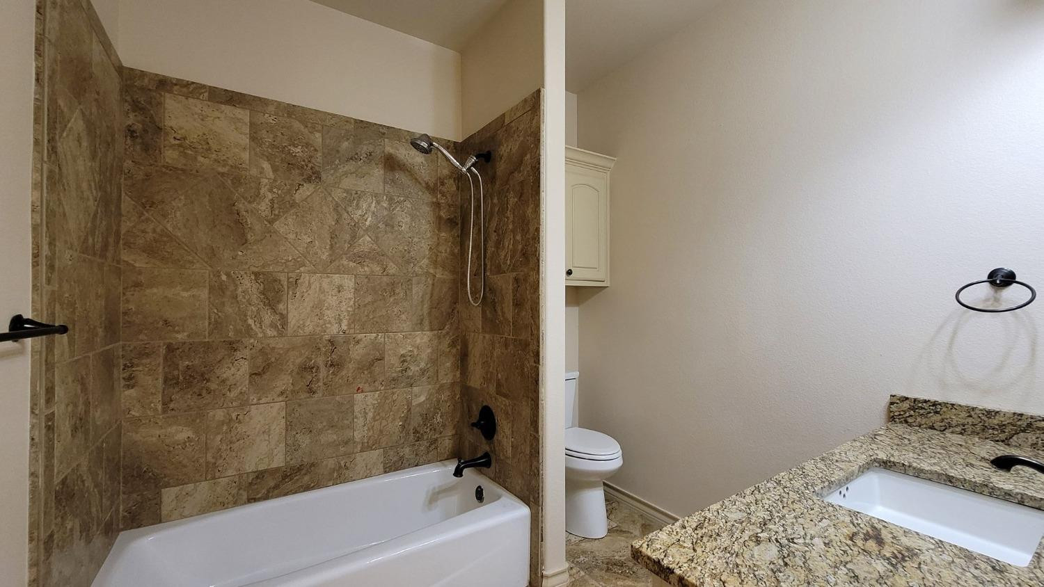5234 Kemper Street Lubbock, TX 79416 - Photo 27 of 28 a bathroom with a tub shower sink and toilet