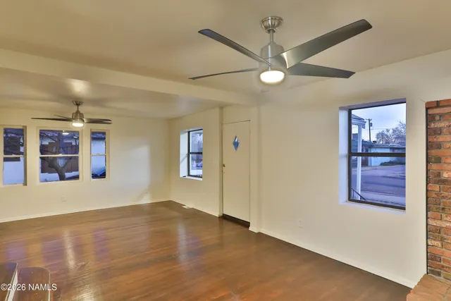 a view of an empty room with a window and wooden floor