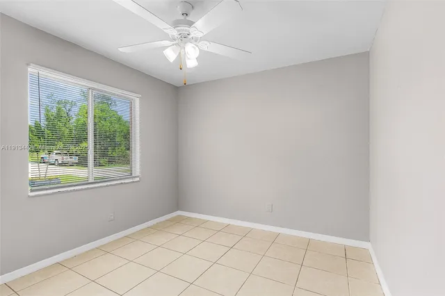 an empty room with windows and chandelier fan