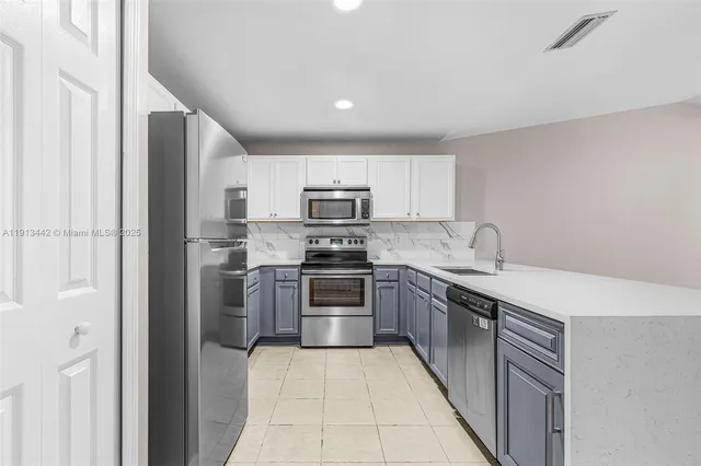 a kitchen with stainless steel appliances granite countertop a refrigerator and a sink