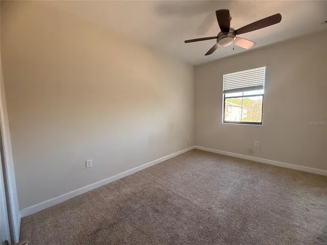 an empty room with a ceiling fan and windows