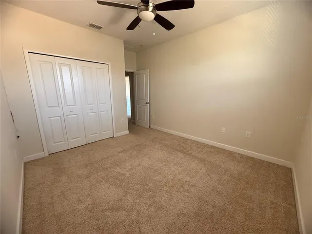 an empty room with a window and a ceiling fan