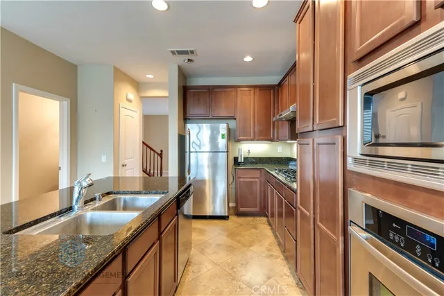 a kitchen with granite countertop a sink a counter top space stainless steel appliances and cabinets