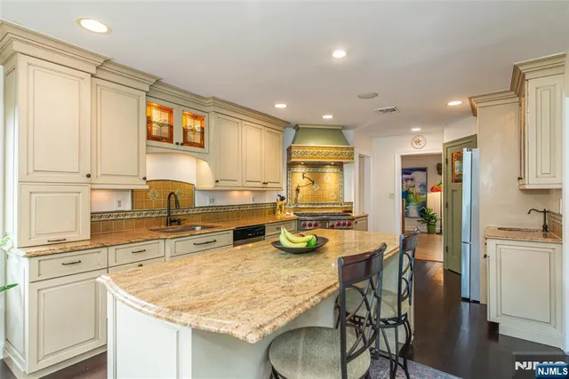 a kitchen with stainless steel appliances granite countertop a table chairs sink and cabinets