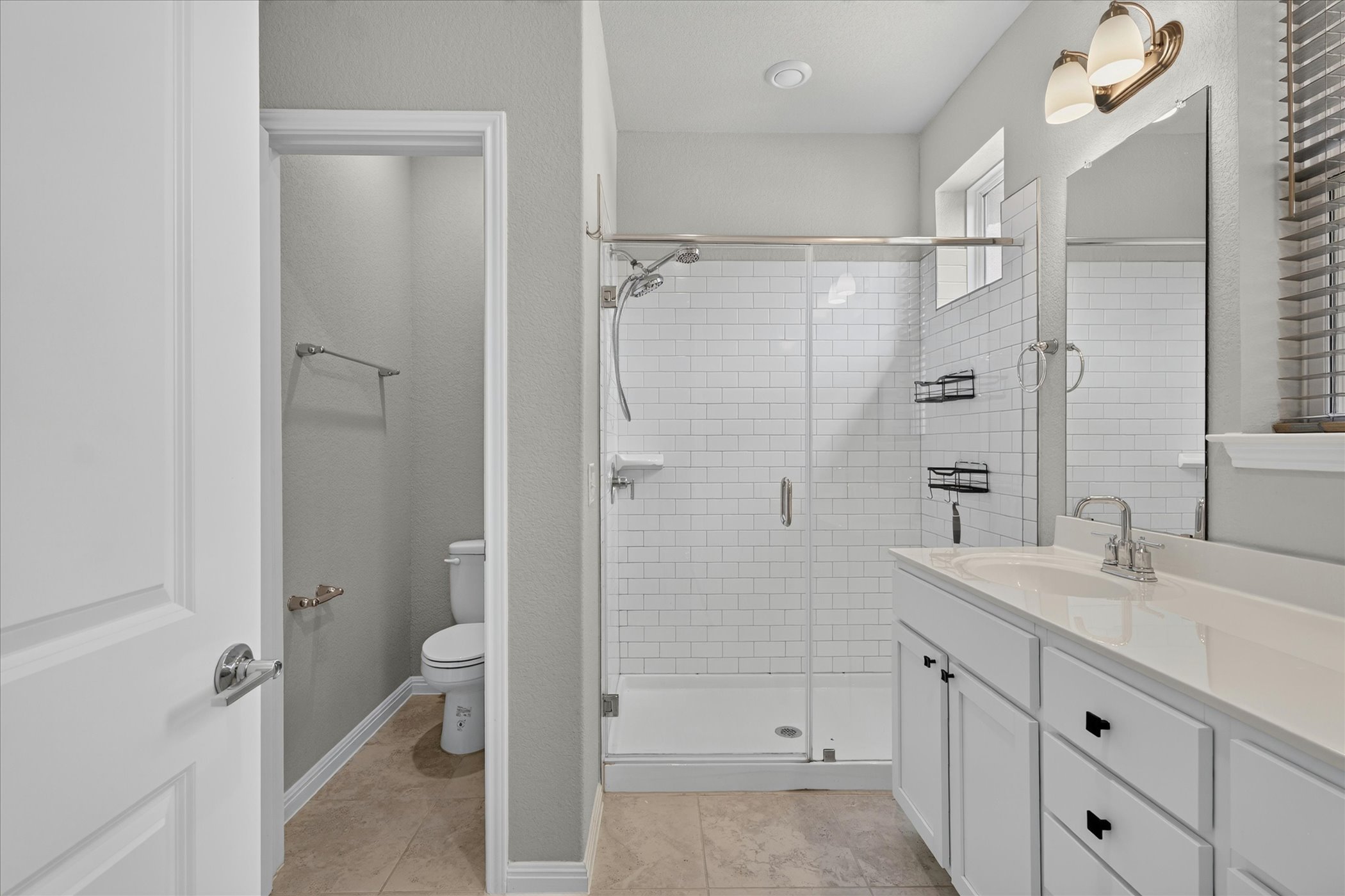 9015 Cattle Baron Path, Unit 1102 Austin, TX 78747 - Photo 12 of 25 A pristine bathroom features a spacious shower with subway tile, complementing a vanity and separate toilet.