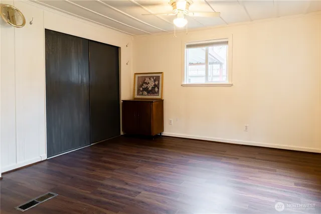 an empty room with wooden floor closet and windows
