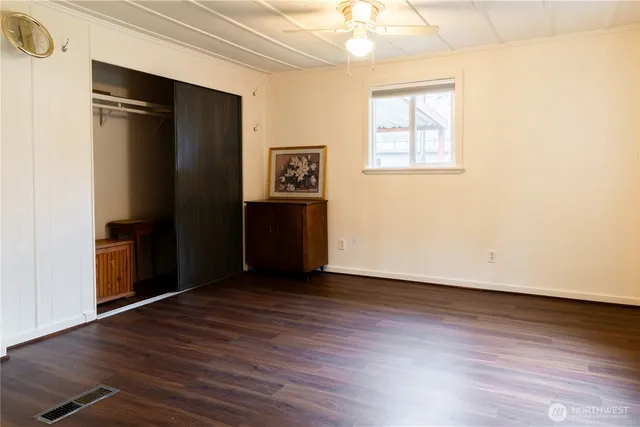 an empty room with wooden floor closet and windows
