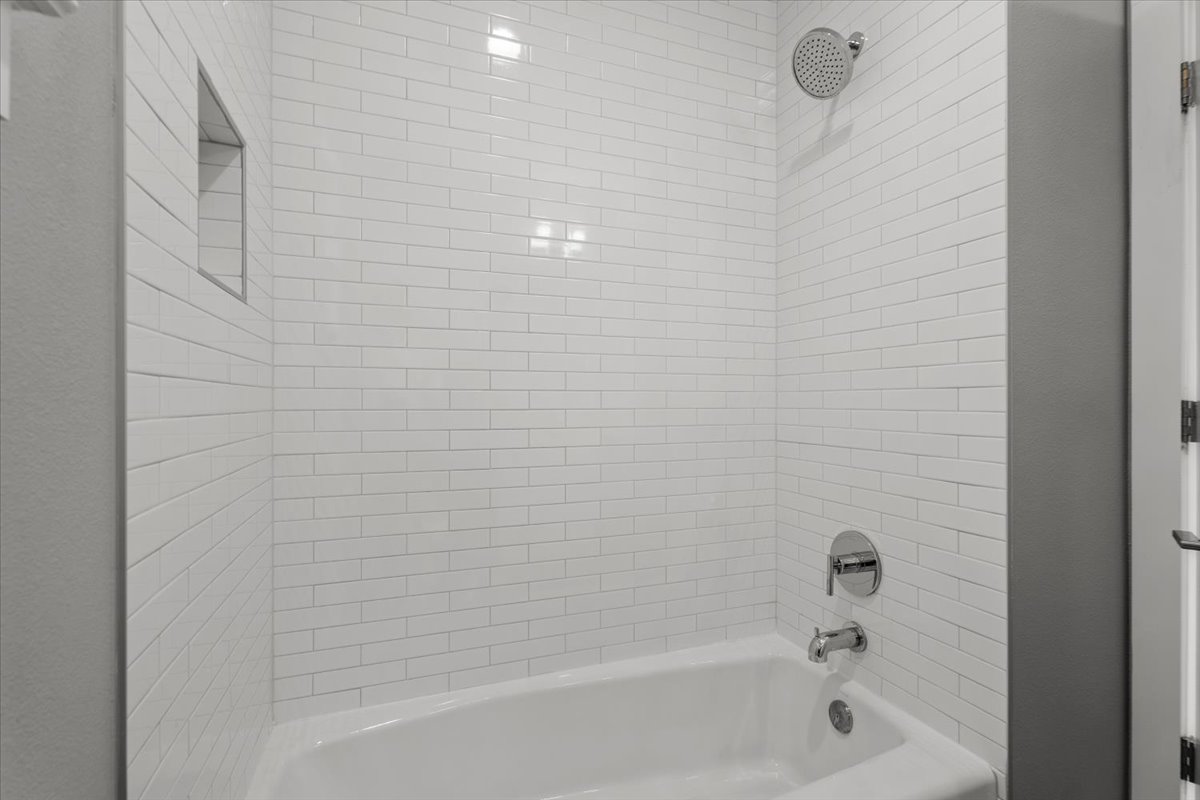 913 Stobaugh Street, Unit B Austin, TX 78757 - Photo 39 of 40 A pristine 3rd bathroom features white subway tile surrounding a classic tub with a built-in shower niche.