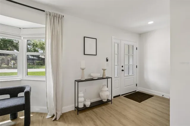 a view of an empty room with window and wooden floor