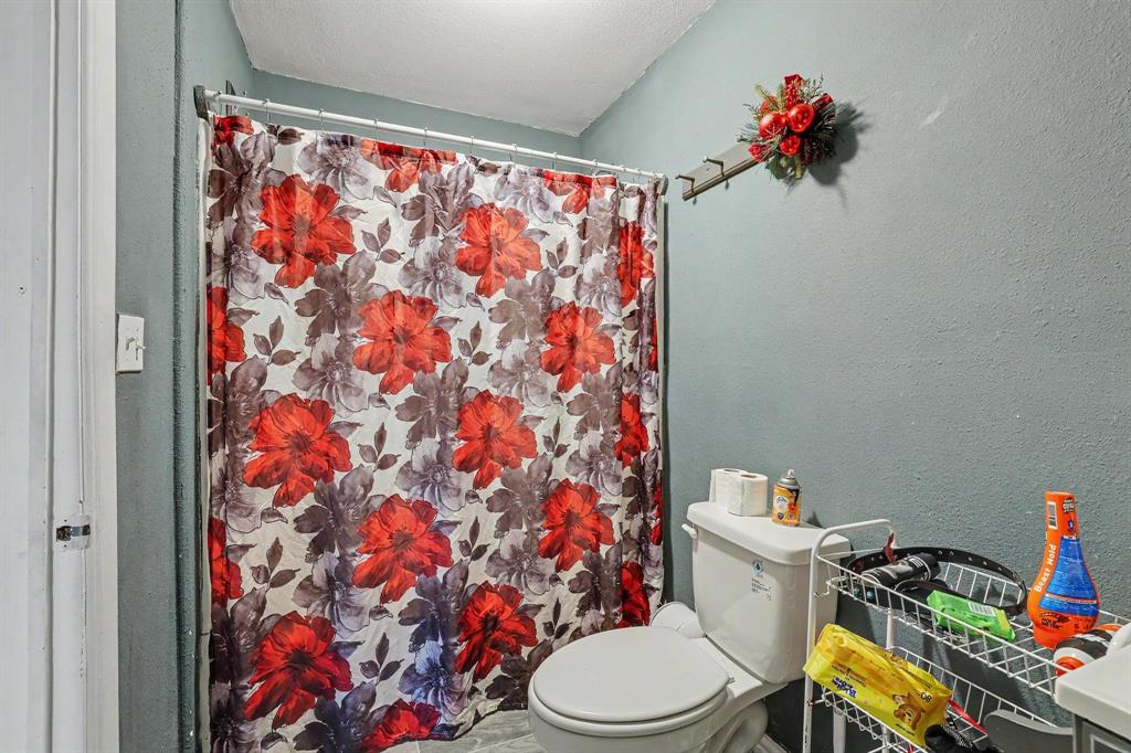 205 South Main Street Bonham, TX 75418 - Photo 18 of 23 a white toilet sitting next to a shower curtain