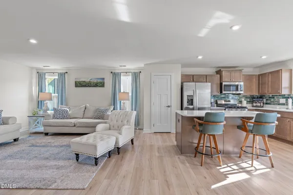 a living room with couches and kitchen view with wooden floor