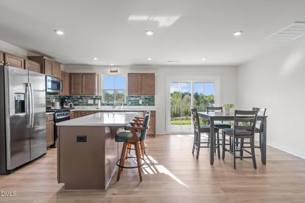 a kitchen with stainless steel appliances granite countertop a table chairs refrigerator and a center island