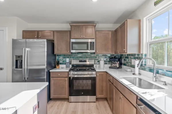 a kitchen with stainless steel appliances granite countertop a sink stove and refrigerator
