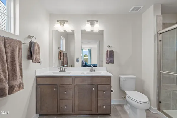 a bathroom with a double vanity sink toilet and a mirror