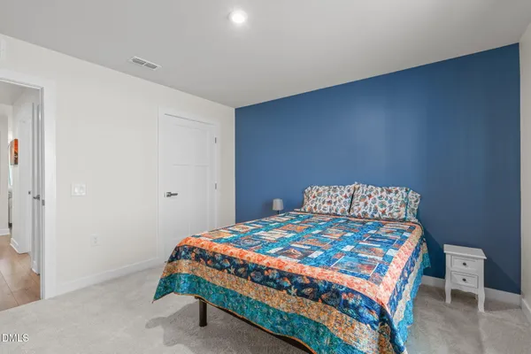 a bedroom with a bed and a lamp on the dresser