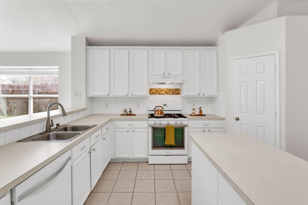 447 Trinity Drive Allen, TX 75002 - Photo 7 of 24 a kitchen with a sink a stove a microwave and cabinets