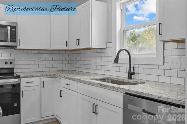 a kitchen with granite countertop a sink a window and cabinets