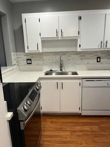 a kitchen with granite countertop a sink a stove and cabinets