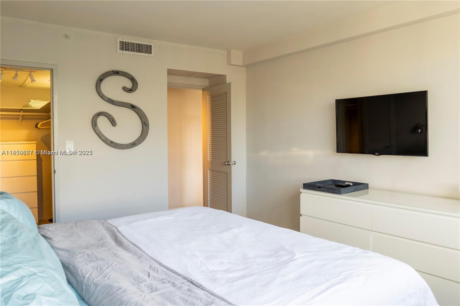 1500 Bay Road, Unit 1464S Miami Beach, FL 33139 - Photo 9 of 13 a bedroom with a bed and a flat screen tv
