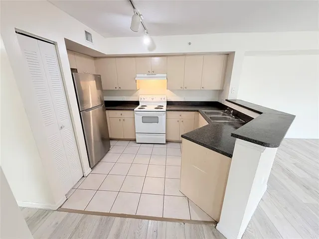 a kitchen with a sink a refrigerator a stove and white cabinets