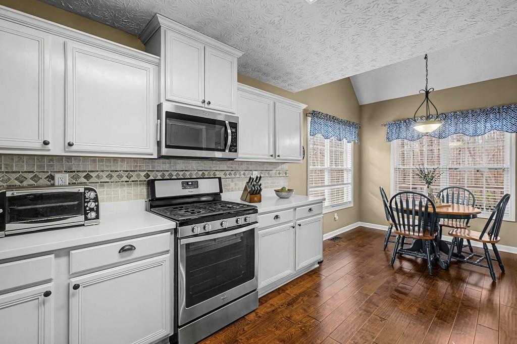 218 Amaranth Court Ball Ground, GA 30107 - Photo 11 of 39 a kitchen with granite countertop wooden floor white cabinets and stainless steel appliances