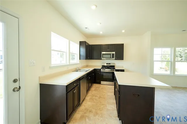 a large kitchen with a sink a counter top space and stainless steel appliances