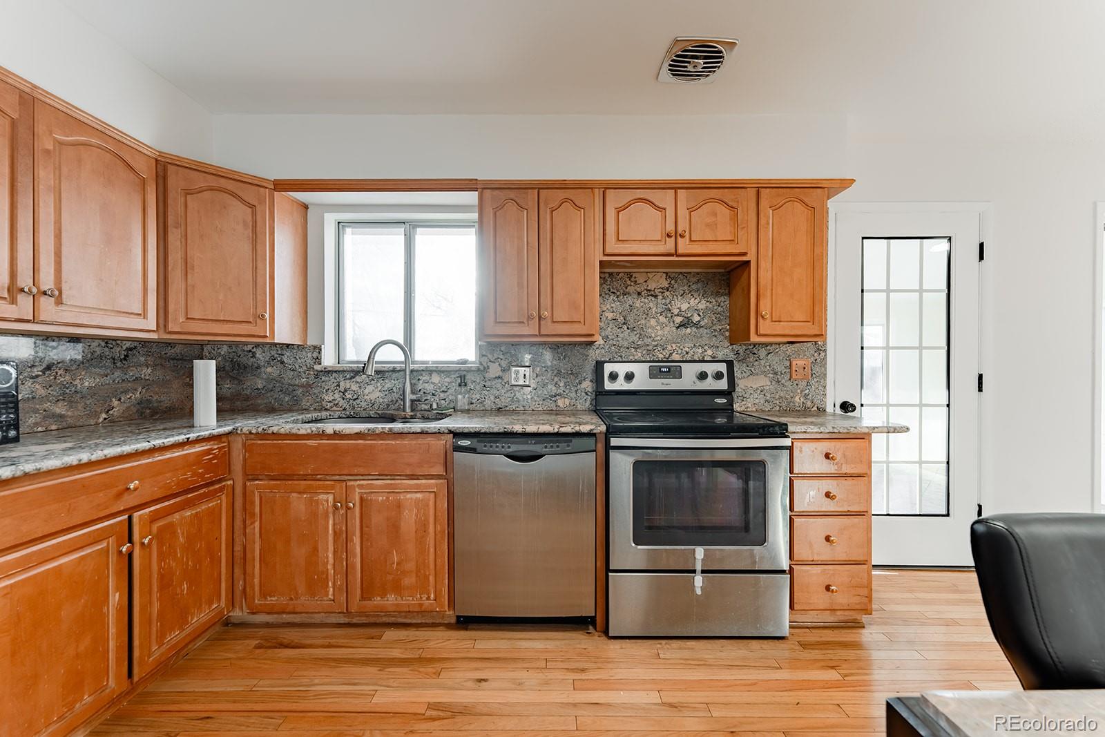 3091 South Yates Street Denver, CO 80236 - Photo 12 of 46 a kitchen with granite countertop a stove and a sink