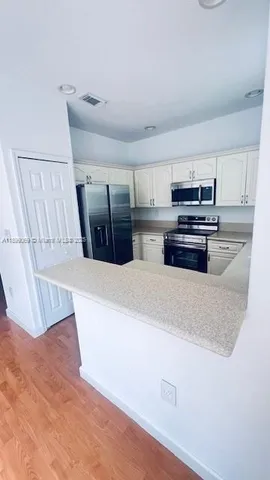 a kitchen with stainless steel appliances cabinets and wooden floor
