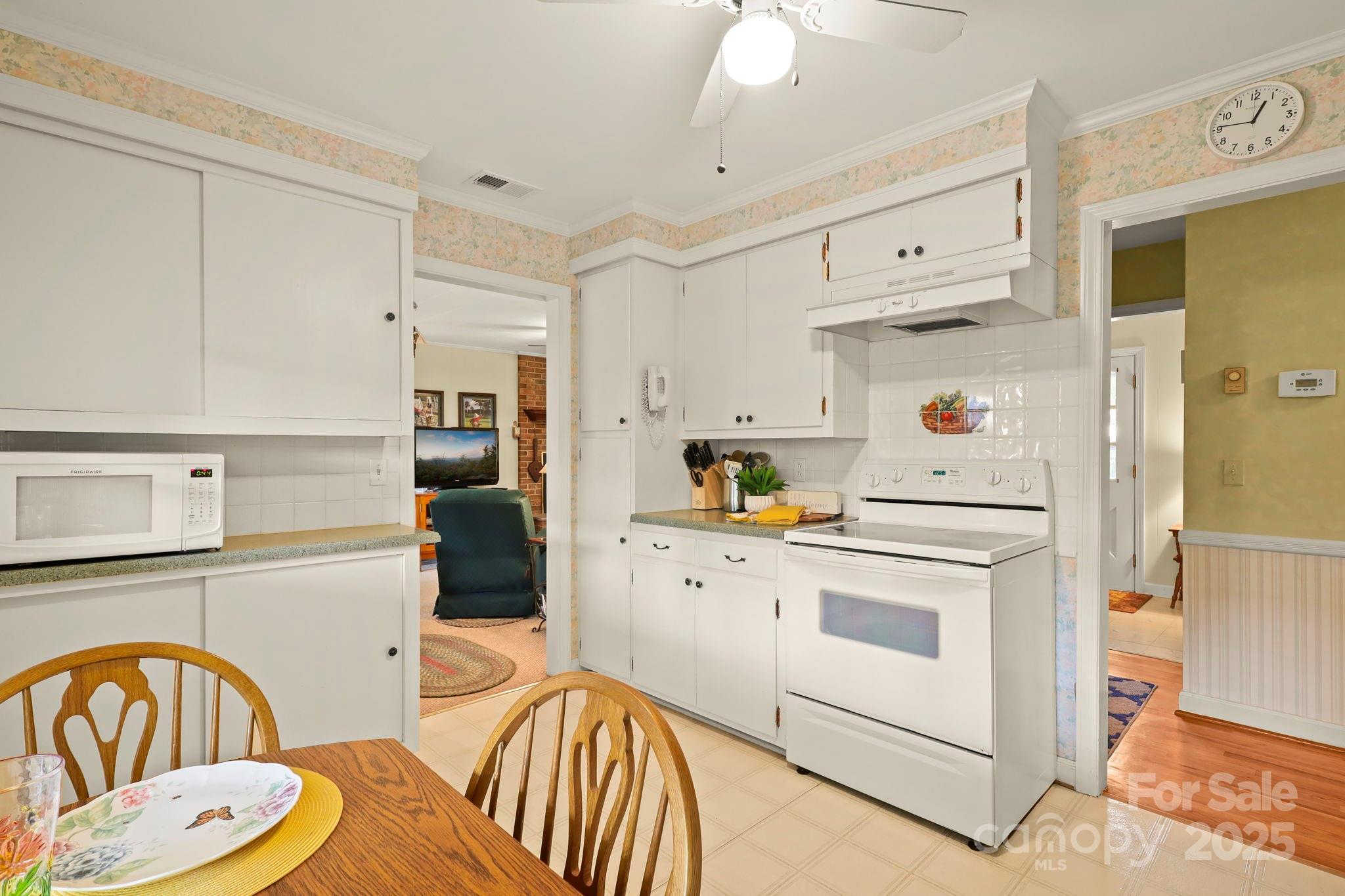 1074 Nikanor Road West Jefferson, NC 28694 - Photo 15 of 45 a kitchen with stainless steel appliances a white refrigerator a sink a stove a dining table and chairs with wooden floor