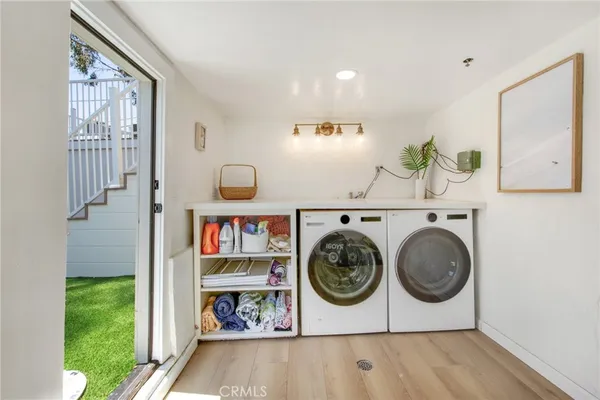 a utility room with fridge and wooden floor