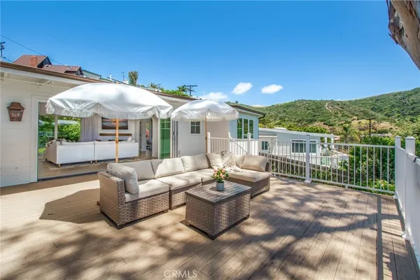 a view of a patio with couches table and chairs under an umbrella with a fire pit
