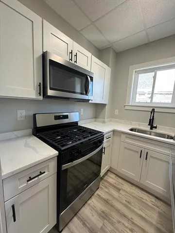 a kitchen with stainless steel appliances white cabinets granite counter tops and a wooden floors