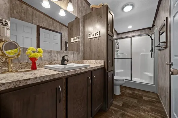 a bathroom with a granite countertop sink a toilet a mirror and shower