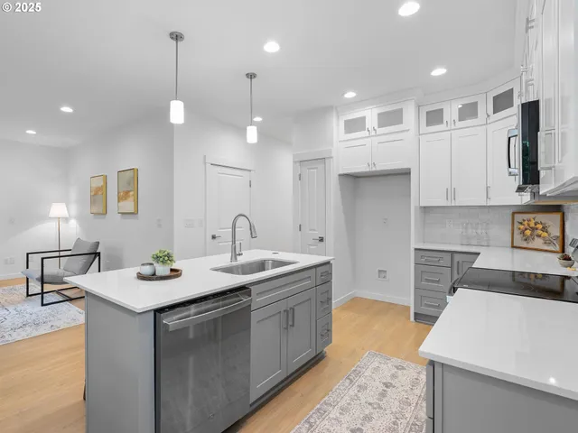 a kitchen that has a lot of white cabinets and stainless steel appliances