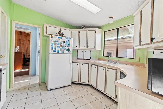 a kitchen with white cabinets and refrigerator