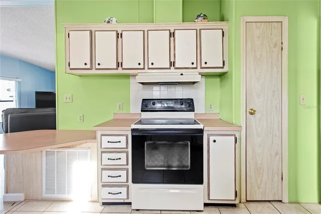 a kitchen with granite countertop a stove top oven and cabinets