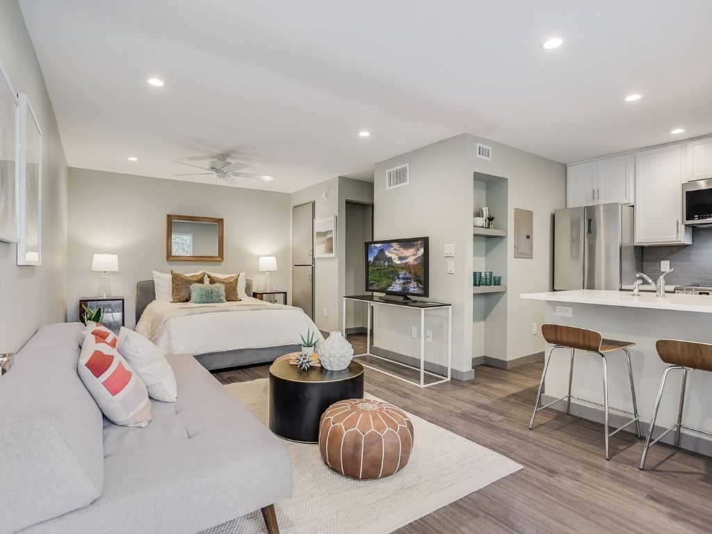 a living room with furniture a flat screen tv and kitchen view