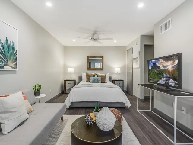 a spacious bedroom with a bed and a flat screen tv