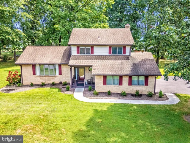 a front view of a house with garden and trees