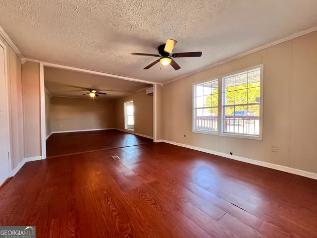 a view of empty room with wooden floor and fan