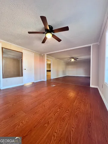 a view of empty room with wooden floor and fan