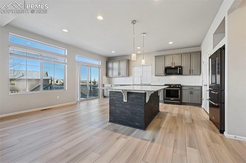 6640 Backcountry Loop Colorado Springs, CO 80927 - Photo 14 of 49 a large kitchen with stainless steel appliances kitchen island a large counter top and a stove